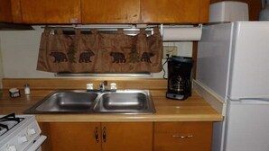 Une cuisine avec des meubles de rangement en bois, un évier à deux bacs, une cuisinière et un réfrigérateur.