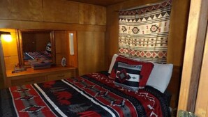 Une pièce comprenant un lit, une commode en bois, un miroir et un rideau à motifs.
