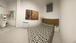 A bedroom with a bed, a wardrobe, a radiator, and a wall-mounted artwork.