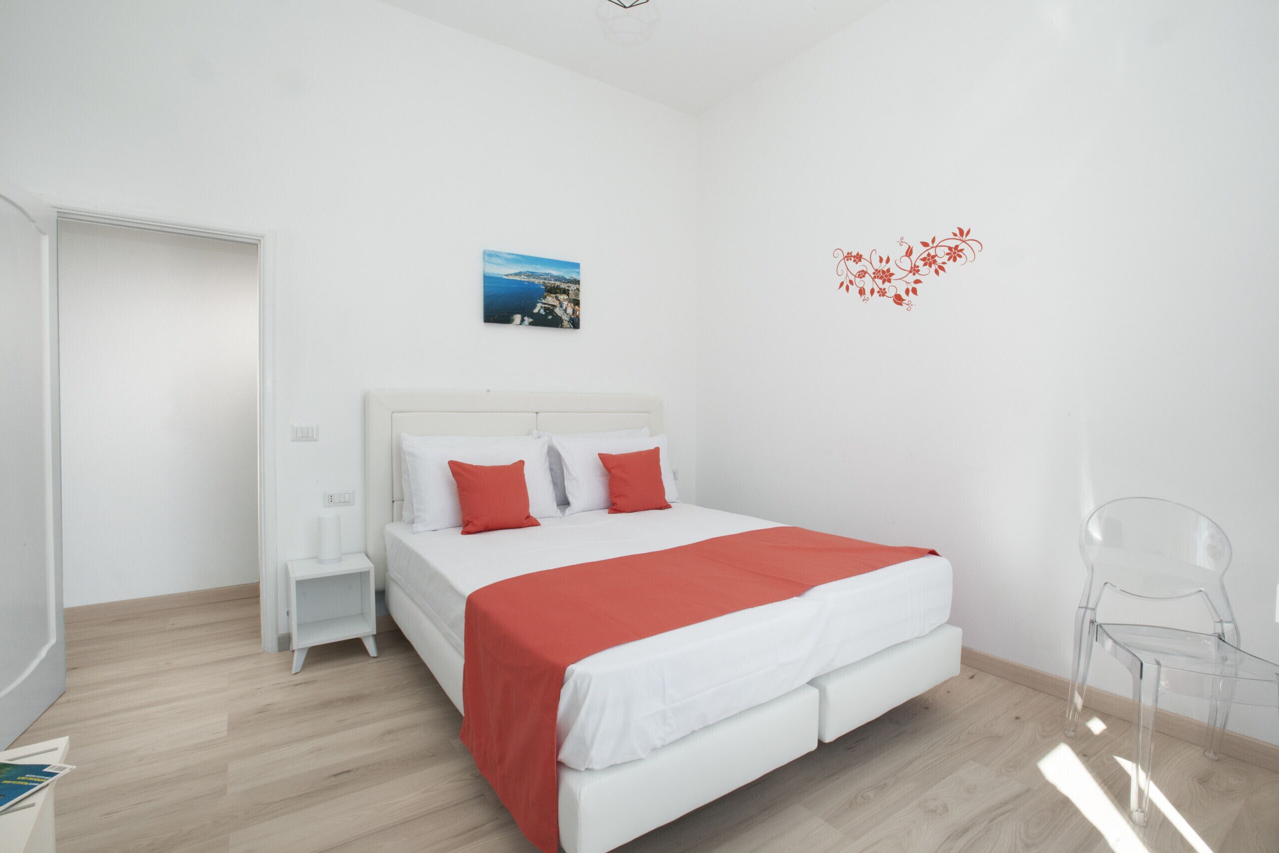 A modern bedroom with a large bed, white walls, and a small nightstand.
