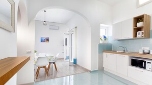 A modern kitchen with white cabinetry, a wooden countertop, and a built-in microwave. - Estate4home - Maison Jenny (Positano)