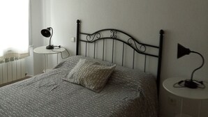 A neatly arranged bedroom with a bed, two bedside tables, a wall-mounted lamp, and a decorative piece above the bed. - VuT Rupurupay A (Aldeadávila de la Ribera)