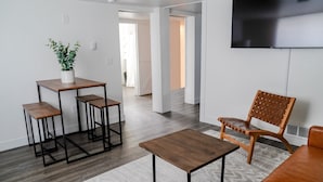 Ein modernes Wohnzimmer mit einem Holzesstisch, einem braunen Sessel und einer Topfpflanze.