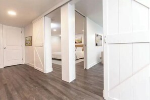 A spacious room with a wooden floor, white walls, and a large window. - Glacier Retreat! Modern, Clean Cowispell Flat: Walk to Downtown Kalispell (Kalispell)
