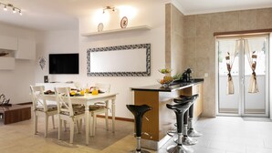 A modern kitchen with a dining area, a bar, and a TV mounted on the wall. - Solange' Place - 300 metres from Nazaré Beach (Nazaré)