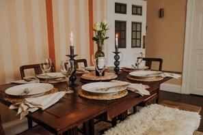 A dining table set with plates, cutlery, and wine glasses, with candles and a vase of flowers.