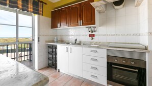 Eine Küche mit weißen Schränken, einem Edelstahlbackofen und Blick durch die Tür.