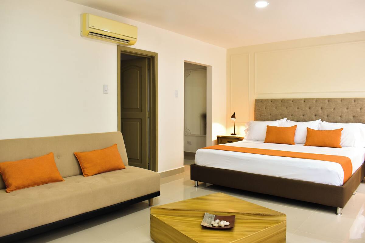 A hotel room with a bed, a sofa, and a coffee table.