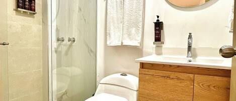 Un baño moderno con ducha envuelta en vidrio, inodoro blanco y armarios de madera.