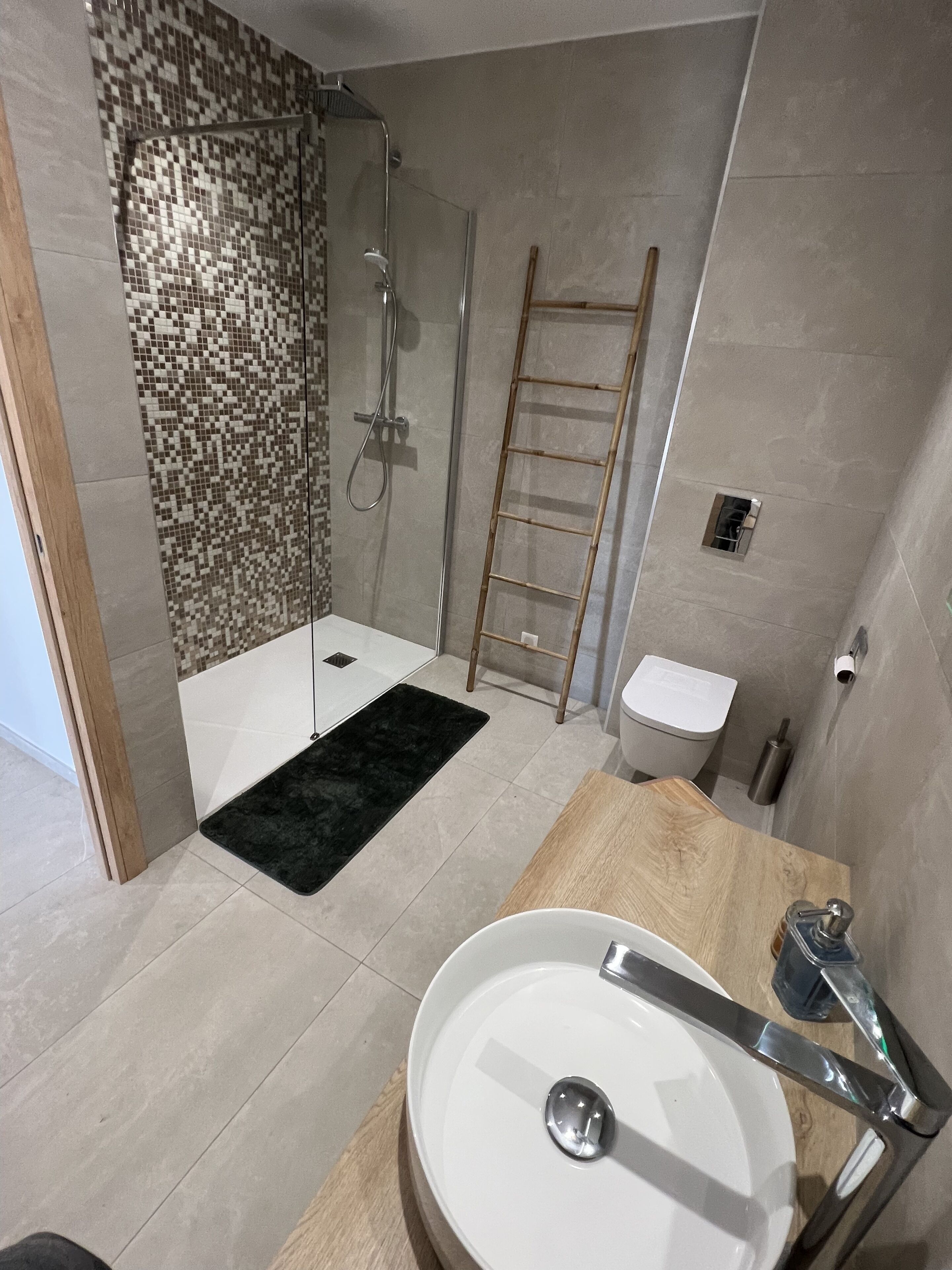 A modern bathroom with a shower, toilet, and sink.