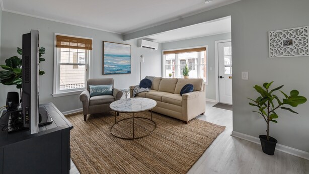 Een moderne woonkamer met een beige bank, een ronde salontafel en een grijze fauteuil.