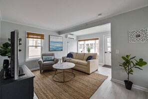 Ein modernes Wohnzimmer mit einem beigefarbenen Sofa, einem runden Couchtisch und einem grauen Sessel.