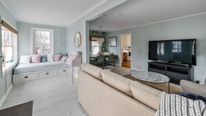 Een ruime woonkamer met een bank, een televisie en een eethoek.