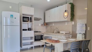 A modern kitchen with a built-in refrigerator, microwave, stove, and oven. There is a dining area with a table and chairs.