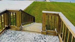 A wooden deck leading to a grassy area with a view of the beach and a pier. - Navarre Beach Front Whole House Large Yard. Kayaks + Paddle Boards Included.  (Navarre)