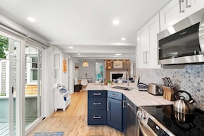 A modern kitchen with a built-in oven, a microwave, and a stainless steel range hood. - Short Walk to Private Association Beach! (Eastham)