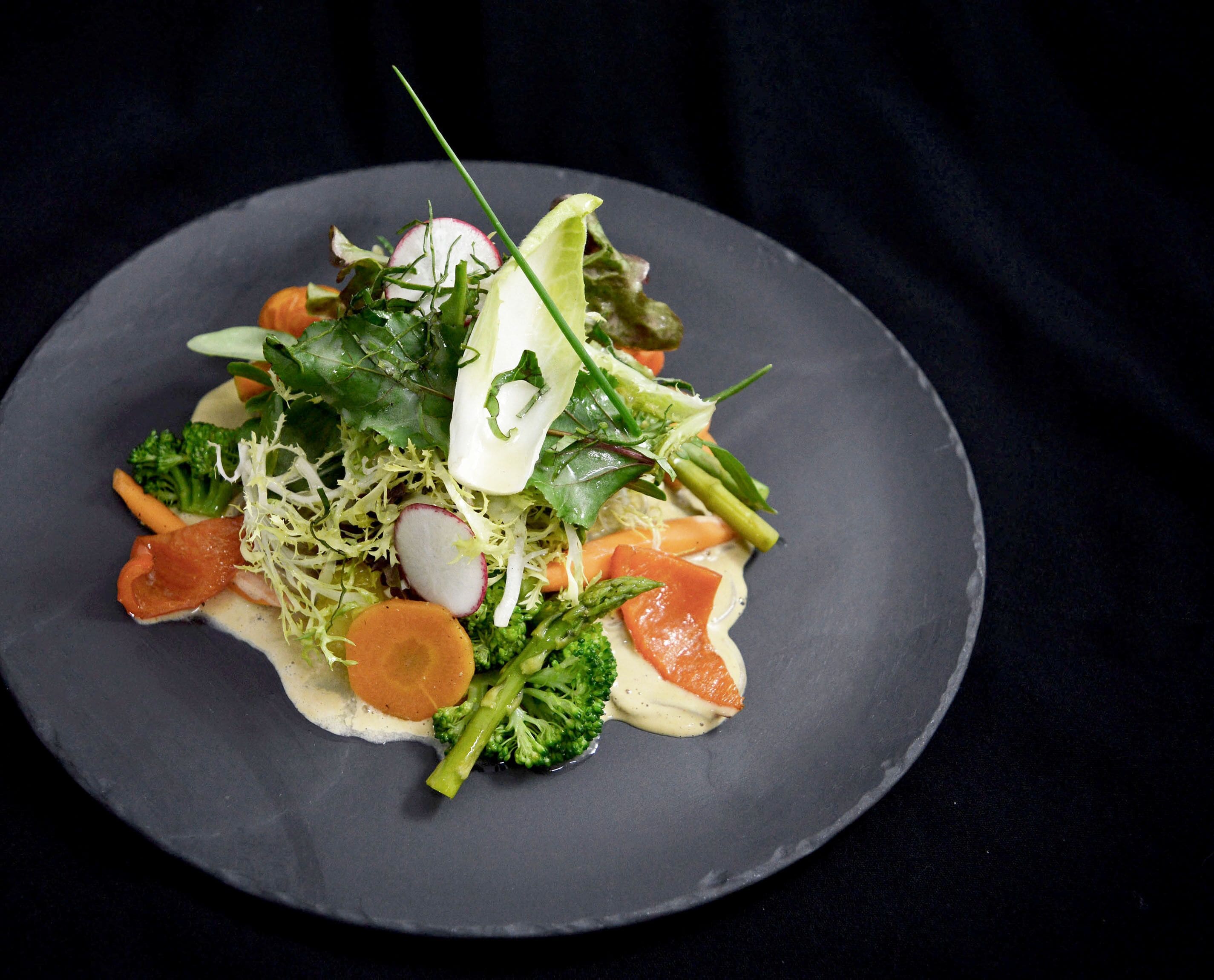 A plate of food with various vegetables and a piece of salmon.