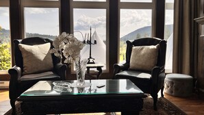 Una habitación con dos sillones de cuero, una mesa de centro de vidrio y un jarrón con flores blancas.