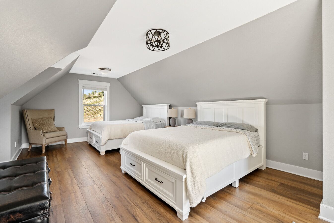 A bedroom with two beds, a chair, and a lamp.
