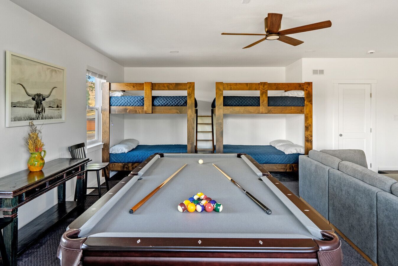 A pool room with bunk beds, a pool table, and a ceiling fan.