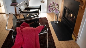 A living room with a black sofa, a red throw blanket, a vase with flowers, and a fireplace. - ‘Star Cottage’ historic, cosy and walking distance to CBD/Salamanca (Sandy Bay)