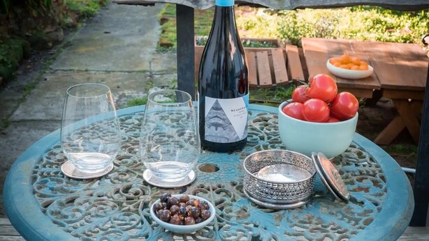 A table set outdoors with a bottle, glasses, a bowl of tomatoes, and olives. - ‘Star Cottage’ historic, cosy and walking distance to CBD/Salamanca (Sandy Bay)