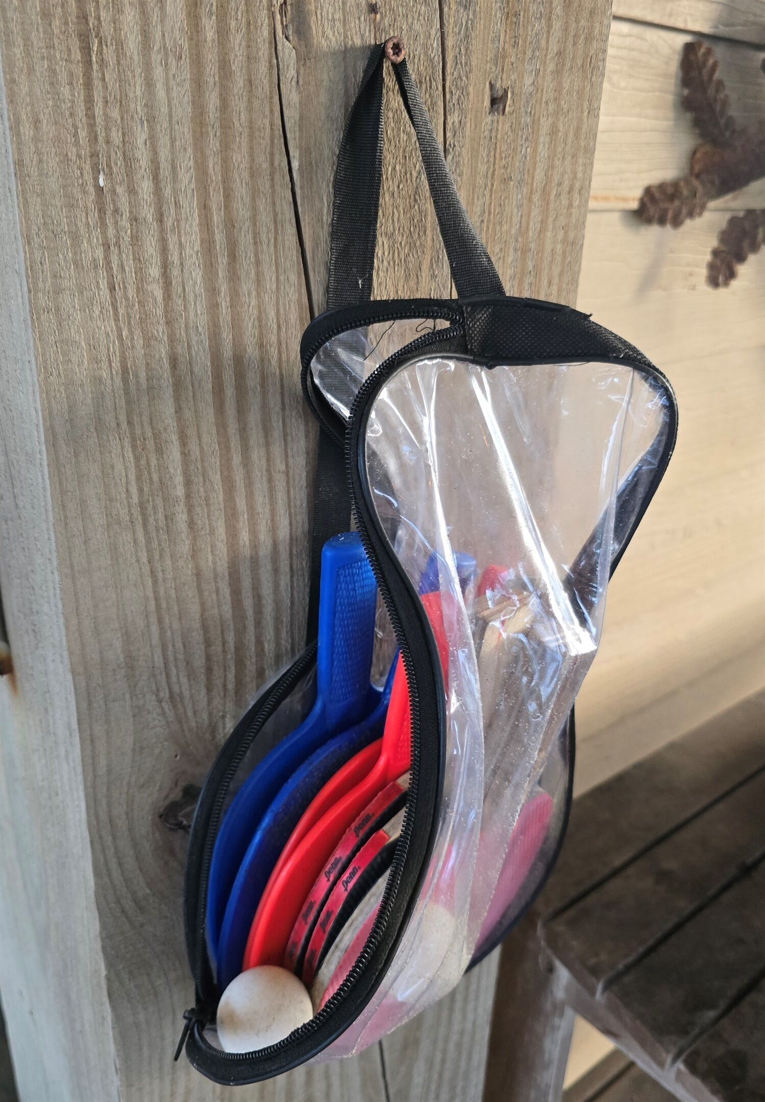 Un sacchetto di plastica trasparente con una tracolla nera appeso a un palo di legno.