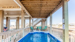 Une piscine couverte dotée d’une terrasse en bois, de chaises et offrant une vue sur la plage.