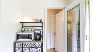 A compact kitchen with a microwave, coffee maker, and storage shelves.