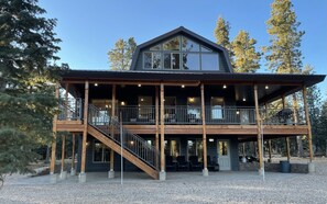 Un chalet à deux étages doté d’un balcon, d’une terrasse en bois et d’un escalier menant à l’étage supérieur.