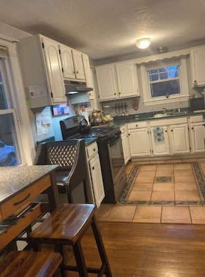 Uma cozinha com armários brancos, bancada preta e mesa de jantar de madeira.