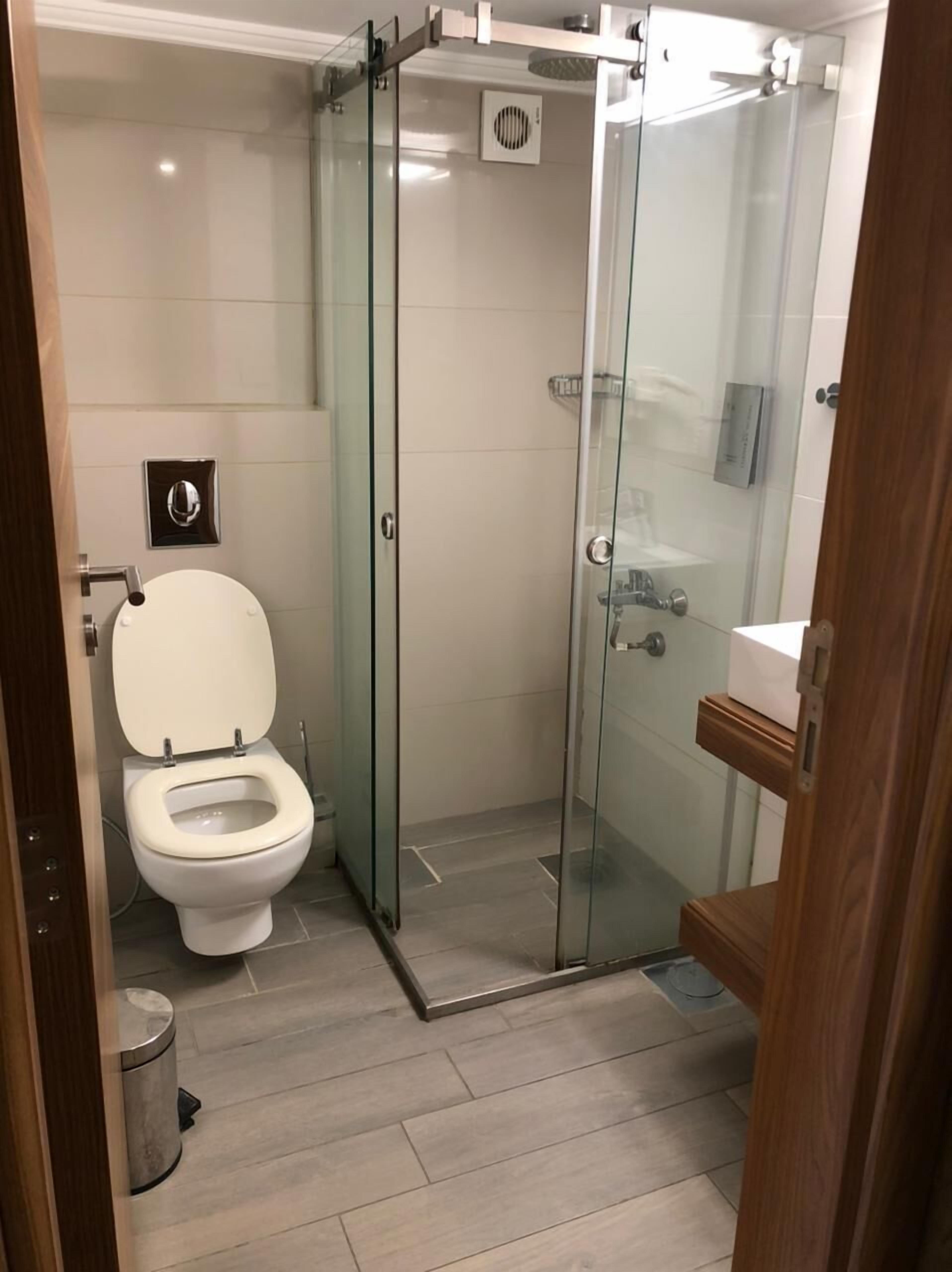 A modern bathroom with a glass-enclosed shower, a toilet, and a sink.