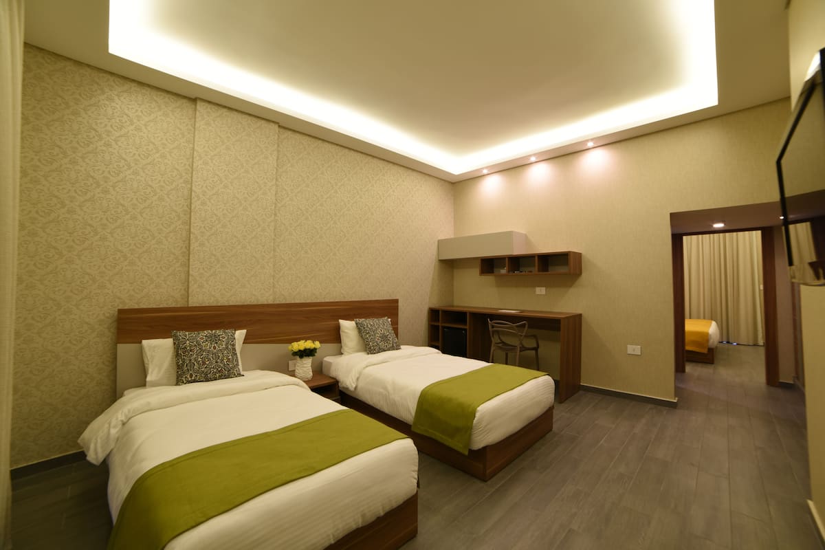 Habitación de hotel con dos camas, un escritorio y una silla.