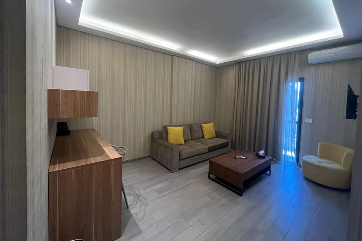 Una sala de estar moderna con un escritorio de madera, un sofá con cojines amarillos, una mesa de centro y una silla.