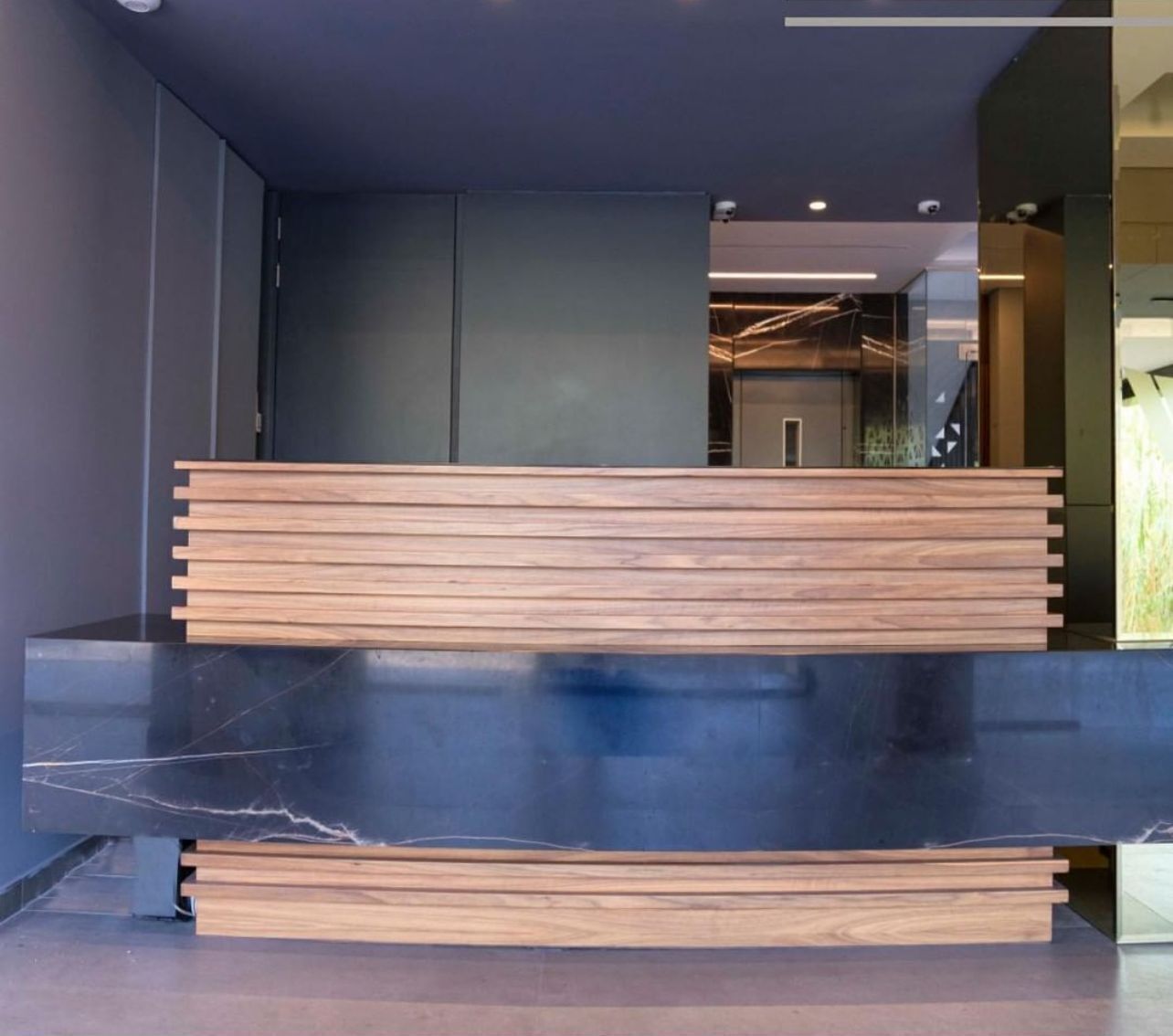 A reception desk with a modern design, featuring a marble base and wooden slats.