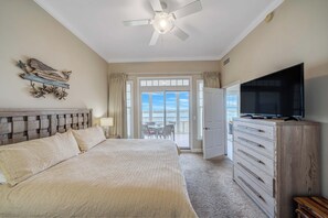 Ein Schlafzimmer mit Bett, Kommode, Fernseher und einem Balkon mit Blick.