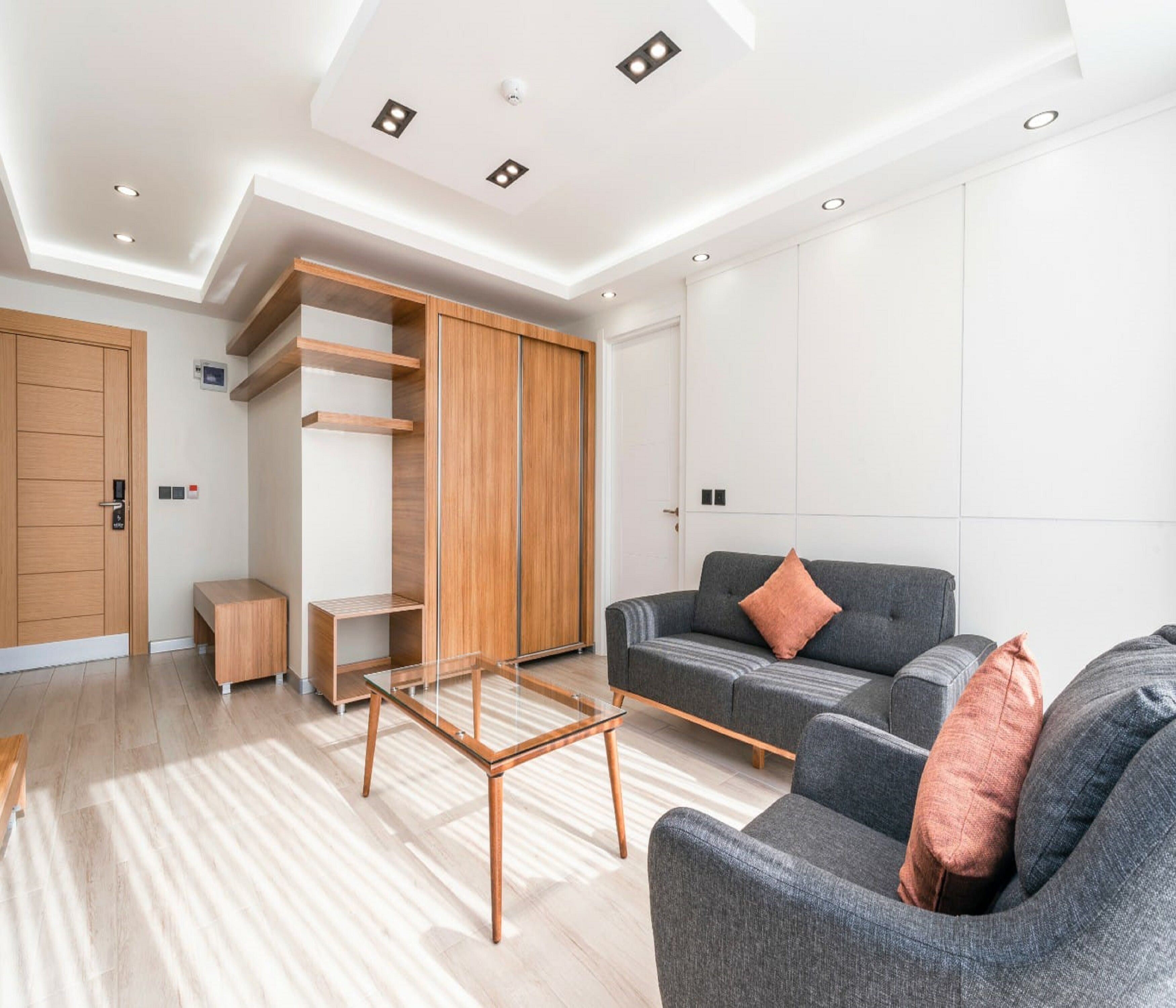 Ein modernes Wohnzimmer mit einem grauen Sofa, einem Holzschrank und einem Glastisch.