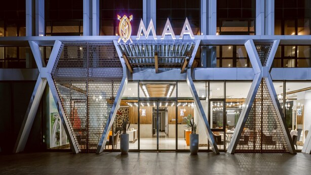 A modern building with a prominent 'MAA' sign, a geometric entrance design, and a well-lit interior visible through glass doors. - Maa Hotel and Suites (Nairobi)