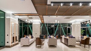 A modern lobby with a high ceiling, geometric patterned ceiling, and a mix of seating areas including sofas and chairs. - Maa Hotel and Suites (Nairobi)