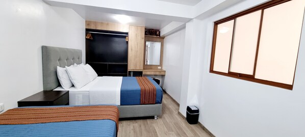A bedroom with two beds, a wardrobe, a mirror, and a window.