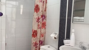 Une salle de bain moderne équipée de toilettes, d’un lavabo et d’un rideau de douche.