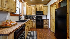 Eine Küche mit Holzausstattung, einem schwarzen Kühlschrank, einer Mikrowelle und einem Geschirrspüler.
