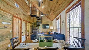 Ein Holzblockbau-Innenraum mit Essbereich, Wohnzimmer und einer Wendeltreppe.