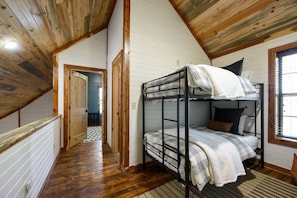 Une chambre avec des lits superposés, des poutres en bois et des murs blancs.