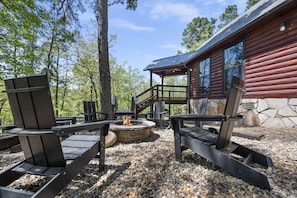 Une cabane en rondins avec une façade en pierre, un foyer et des fauteuils Adirondack.