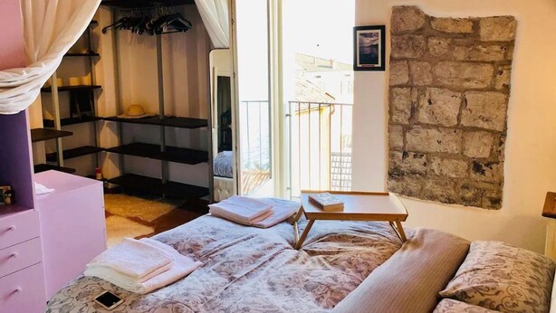 Una camera da letto con un letto, un comodino, un armadio e un balcone.