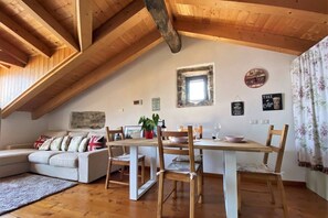 Un acogedor loft con comedor, sofá y un pequeño ventanal de cocina.