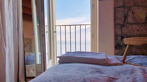A bedroom with a bed, a balcony with a railing, and a view of the sea. - Cà Milla Argegno apartment (Argegno)
