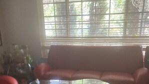 A living room with a glass coffee table, a red sofa, and a window with blinds. - Queen Suite full bath  1-3 guest  minute to school shopping etc .優雅套房。交通方便。赞👍 (Hacienda Heights)