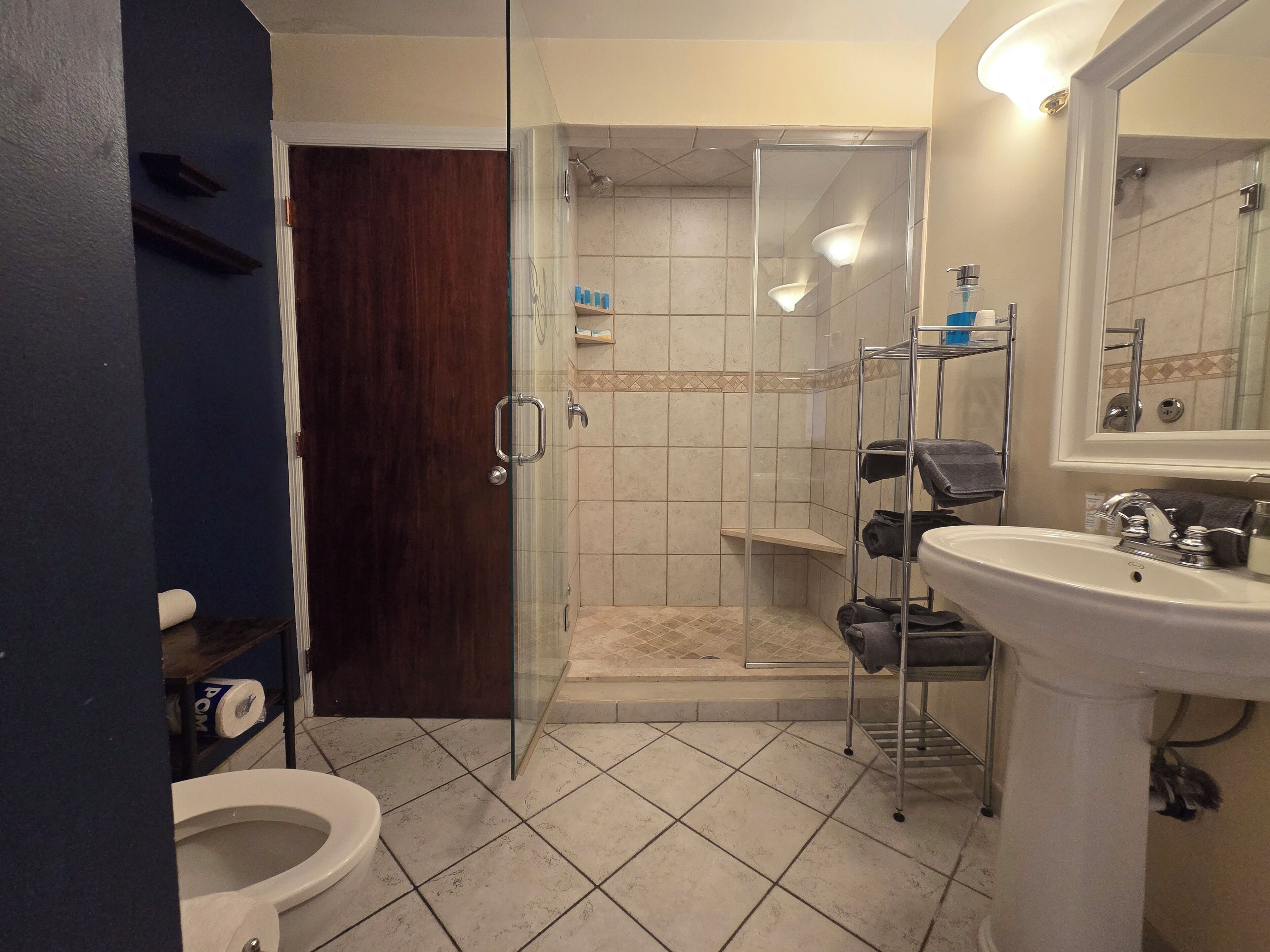 Un baño con ducha envuelta en cristal, un lavabo blanco y un inodoro.